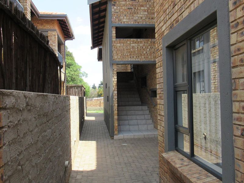 Exterior view of the apartment complex featuring face brick construction, a paved walkway, and a concrete staircase leading to upper levels.