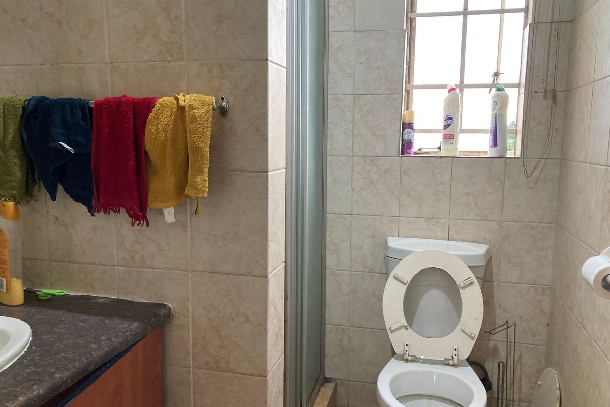 A functional bathroom featuring tiled walls, a shower enclosure, and a vanity countertop, currently requiring cosmetic updates to improve its overall condition.