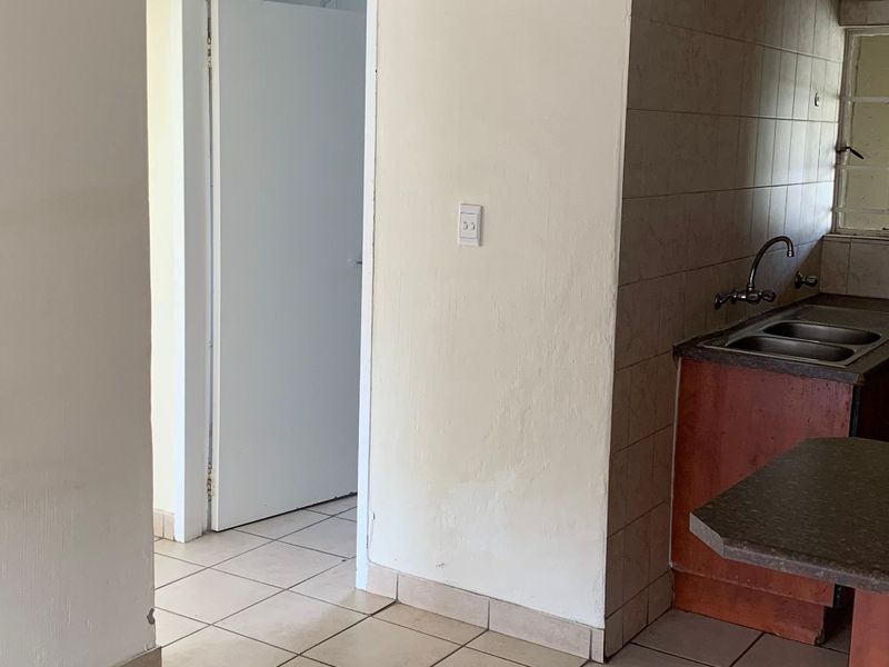 A functional kitchen area featuring tiled flooring, a double bowl sink, and built-in cabinetry, currently vacant and ready for updates.