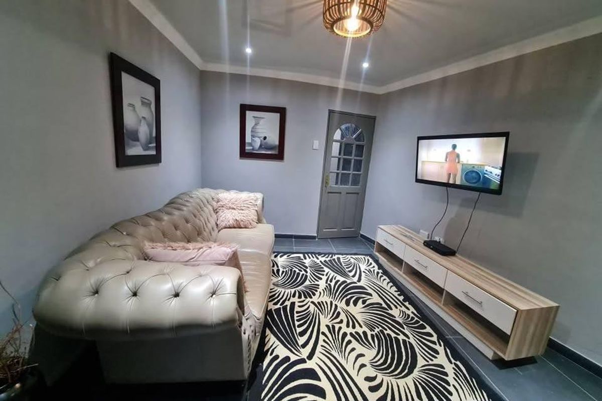 A well-maintained living room featuring tiled flooring, coved ceilings, and recessed lighting, providing a comfortable and functional space.