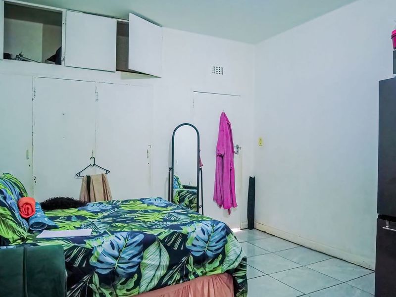 A bedroom featuring tiled flooring and built-in storage cupboards with overhead compartments.