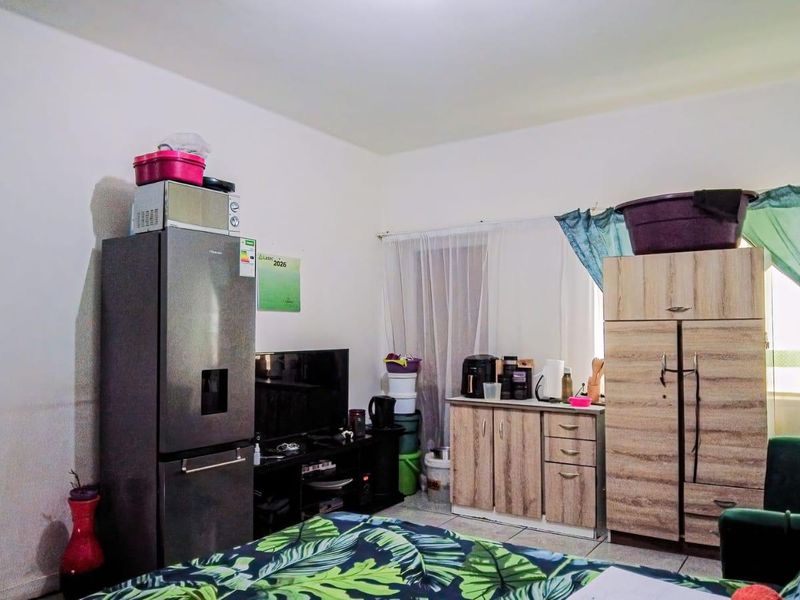 A living area featuring tiled flooring and neutral wall finishes, currently utilized with various storage and household items.