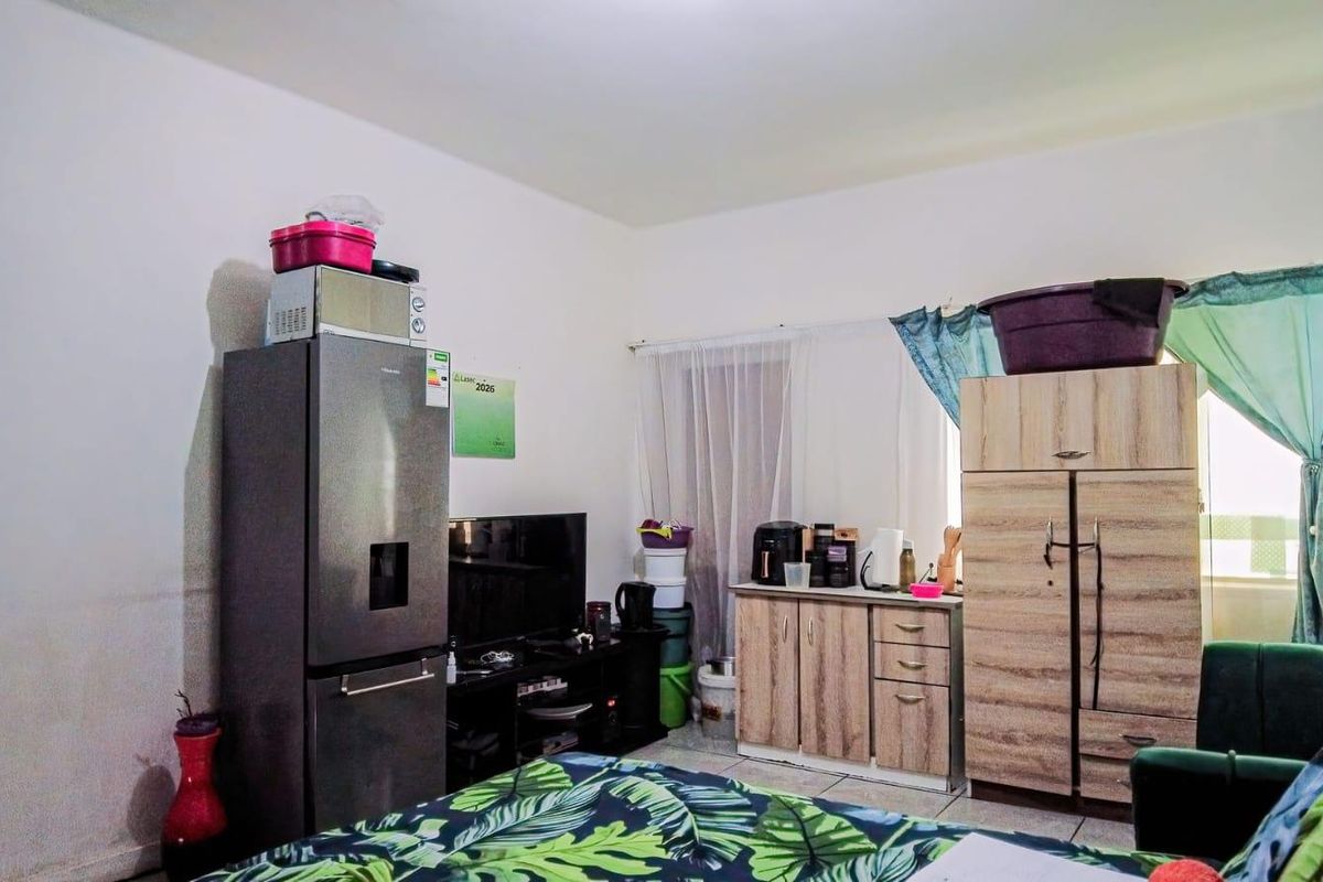 A living area featuring tiled flooring and neutral wall finishes, currently utilized with various storage and household items.