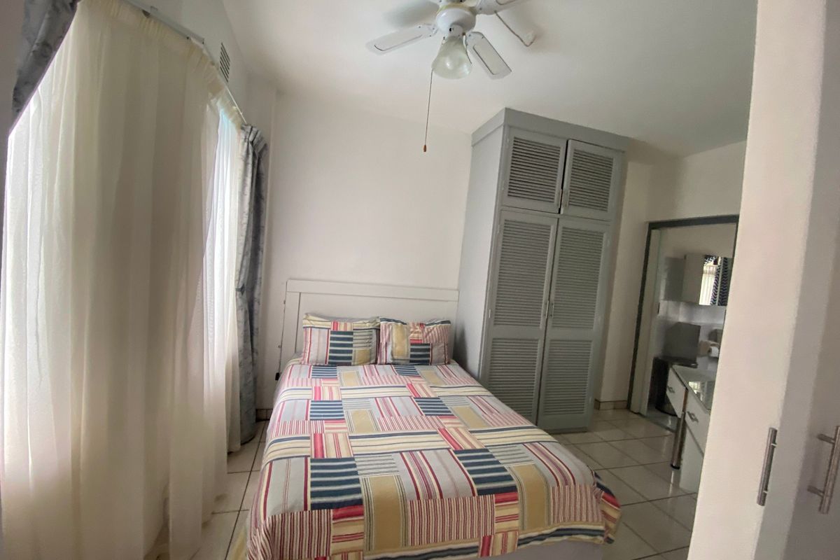 A bedroom featuring tiled flooring, a ceiling fan, and a built-in wardrobe with louvered doors.