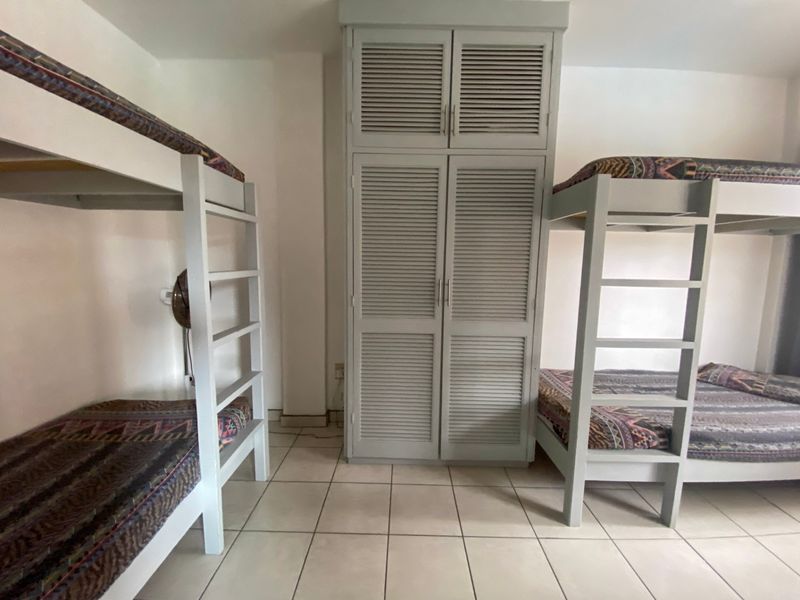A bedroom featuring tiled flooring and a tall, built-in louvered wardrobe providing ample storage space.