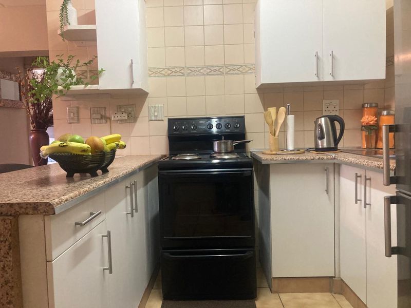 Compact kitchen featuring white cabinetry, laminate countertops, tiled backsplash, and a freestanding stove, offering a functional layout with potential for modern updates.