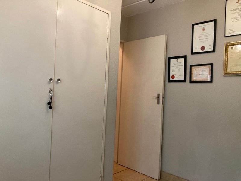 A functional hallway featuring built-in cupboard storage and tiled flooring, providing access to adjacent rooms.