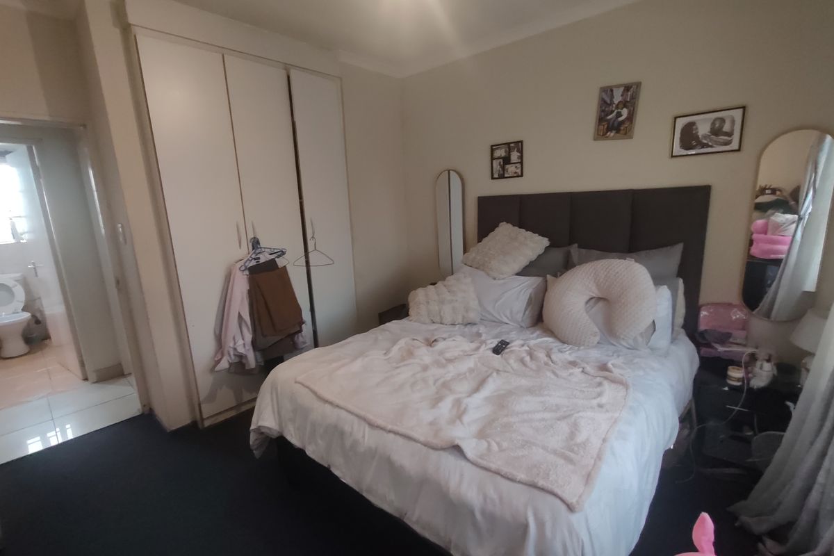 A bedroom featuring built-in cupboards and direct access to an en-suite bathroom, providing a functional layout for a primary or guest suite.