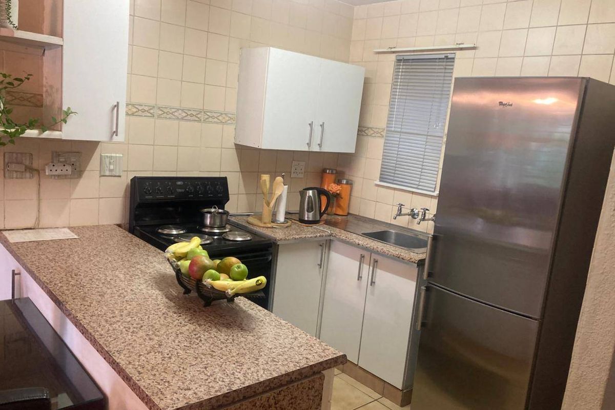 A functional kitchen featuring laminate countertops, tiled backsplash, built-in cabinetry, and a stainless steel sink, offering a practical layout for daily meal preparation.