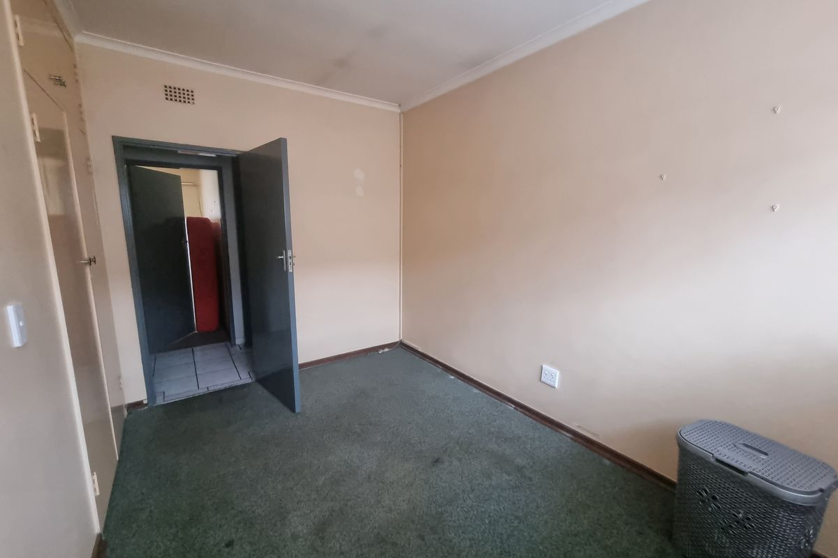 An empty bedroom featuring built-in cupboards, carpeted flooring, and coved cornicing, requiring cosmetic updates to improve its overall condition.