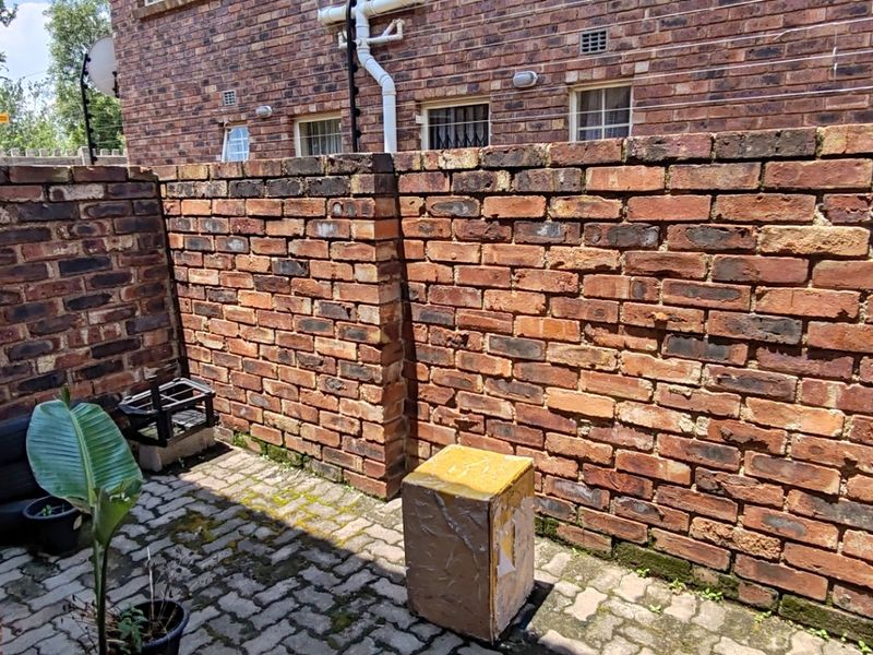 A private rear courtyard featuring exposed brick walls and paved flooring, offering a functional outdoor space for the apartment.