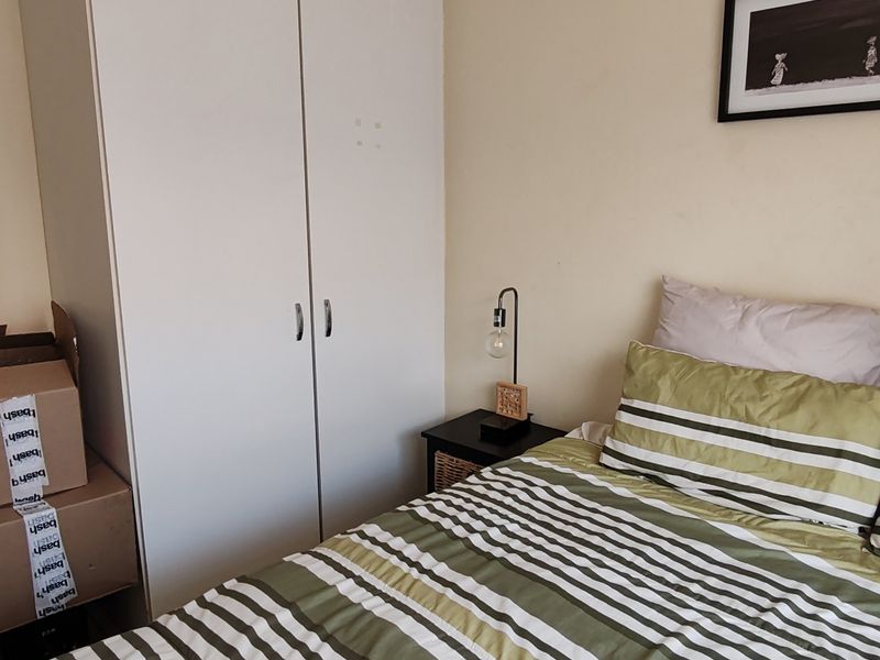A bedroom featuring a built-in wardrobe with white cabinetry, providing functional storage space within the room.
