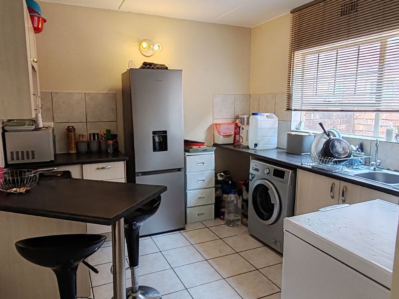 A functional kitchen featuring tiled flooring, built-in cabinetry, a breakfast bar, and a tiled backsplash, offering a practical layout for daily use.