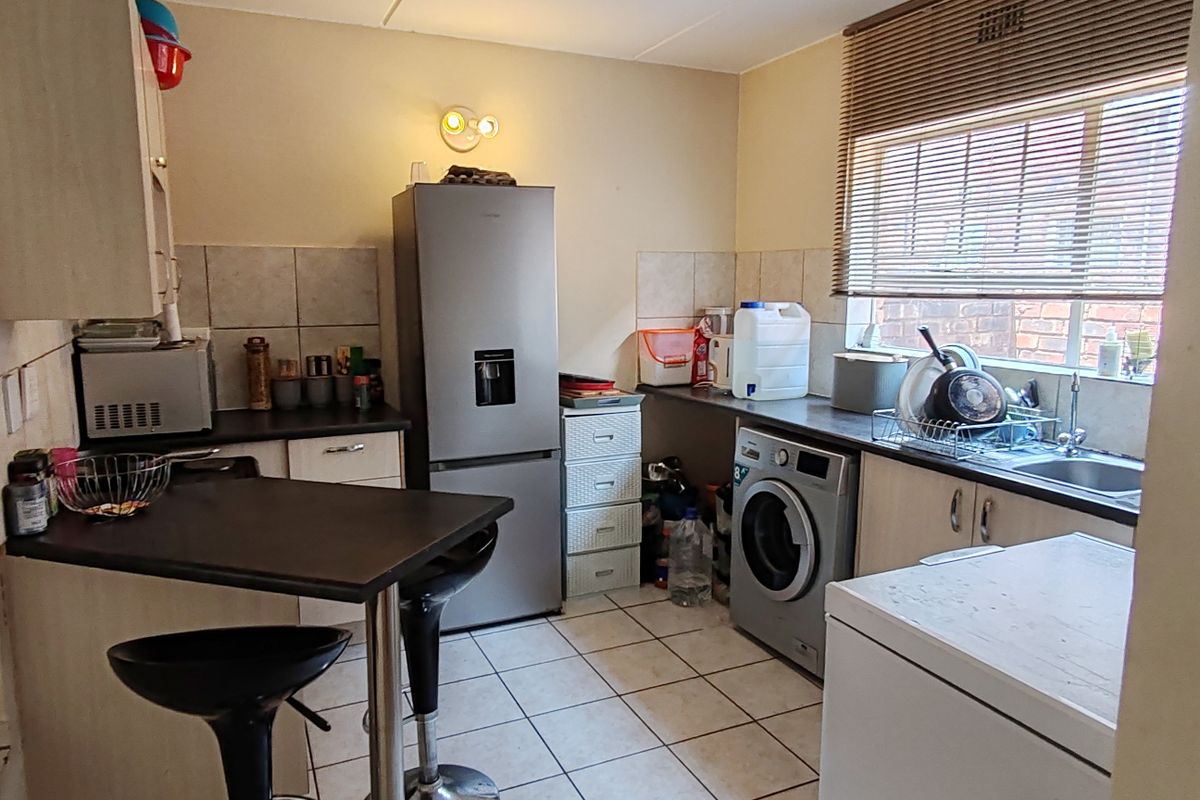 A functional kitchen featuring tiled flooring, built-in cabinetry, a breakfast bar, and a tiled backsplash, offering a practical layout for daily use.