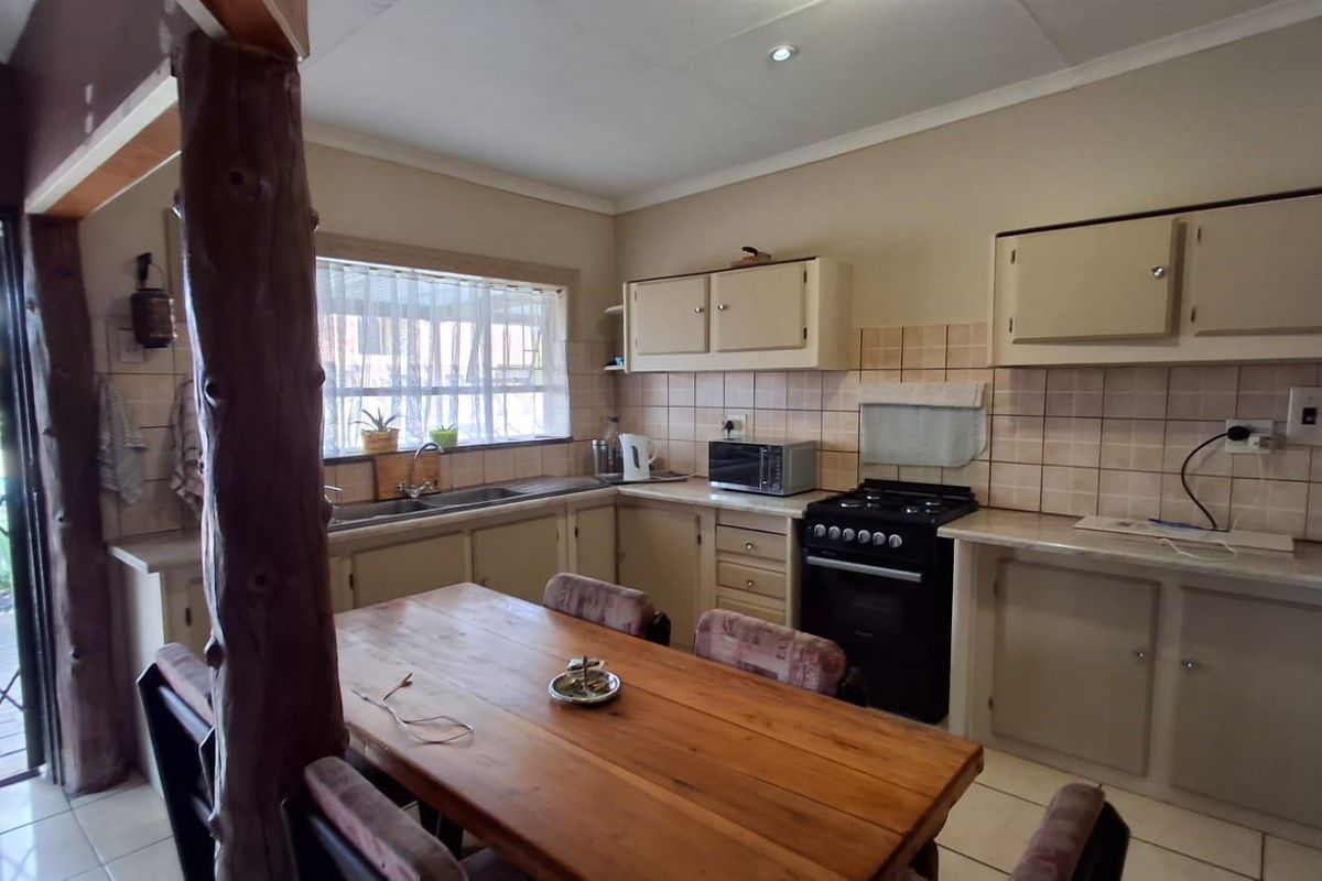 Functional kitchen featuring built-in cabinetry, tiled backsplash, double basin sink, and a freestanding stove, with direct access to an outdoor area.