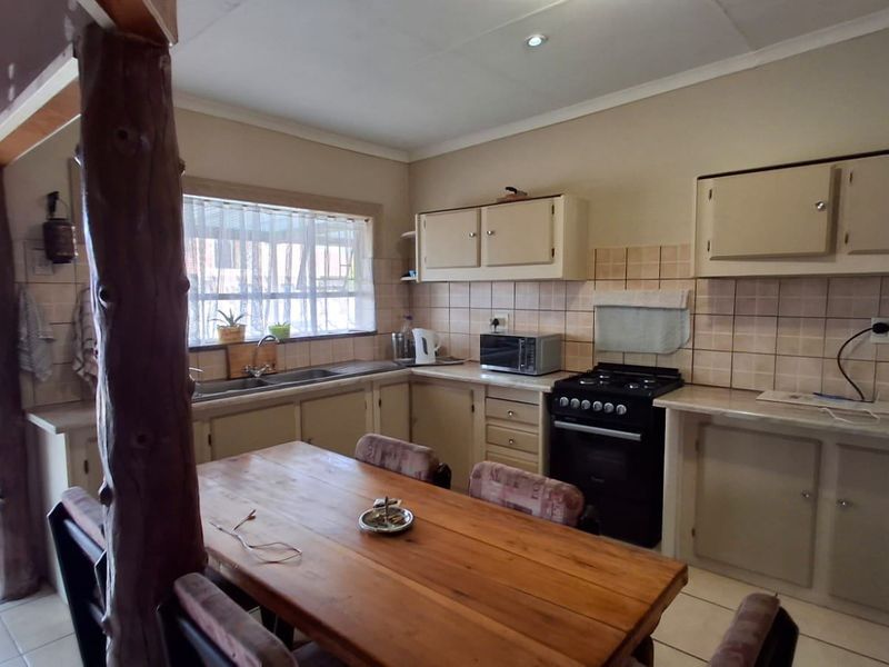 Functional kitchen featuring built-in cabinetry, tiled backsplash, double basin sink, and a freestanding stove, with direct access to an outdoor area.