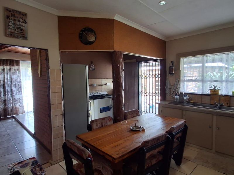 Open plan kitchen and dining area featuring tiled floors, built-in cabinetry, and direct access to an outdoor patio area through a security gate.