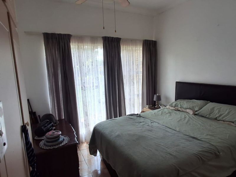 A functional bedroom featuring tiled flooring, a ceiling fan, and a built-in wardrobe, offering a neutral space ready for personalization.