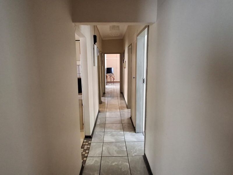 A functional hallway featuring tiled flooring and access to multiple rooms within the property.