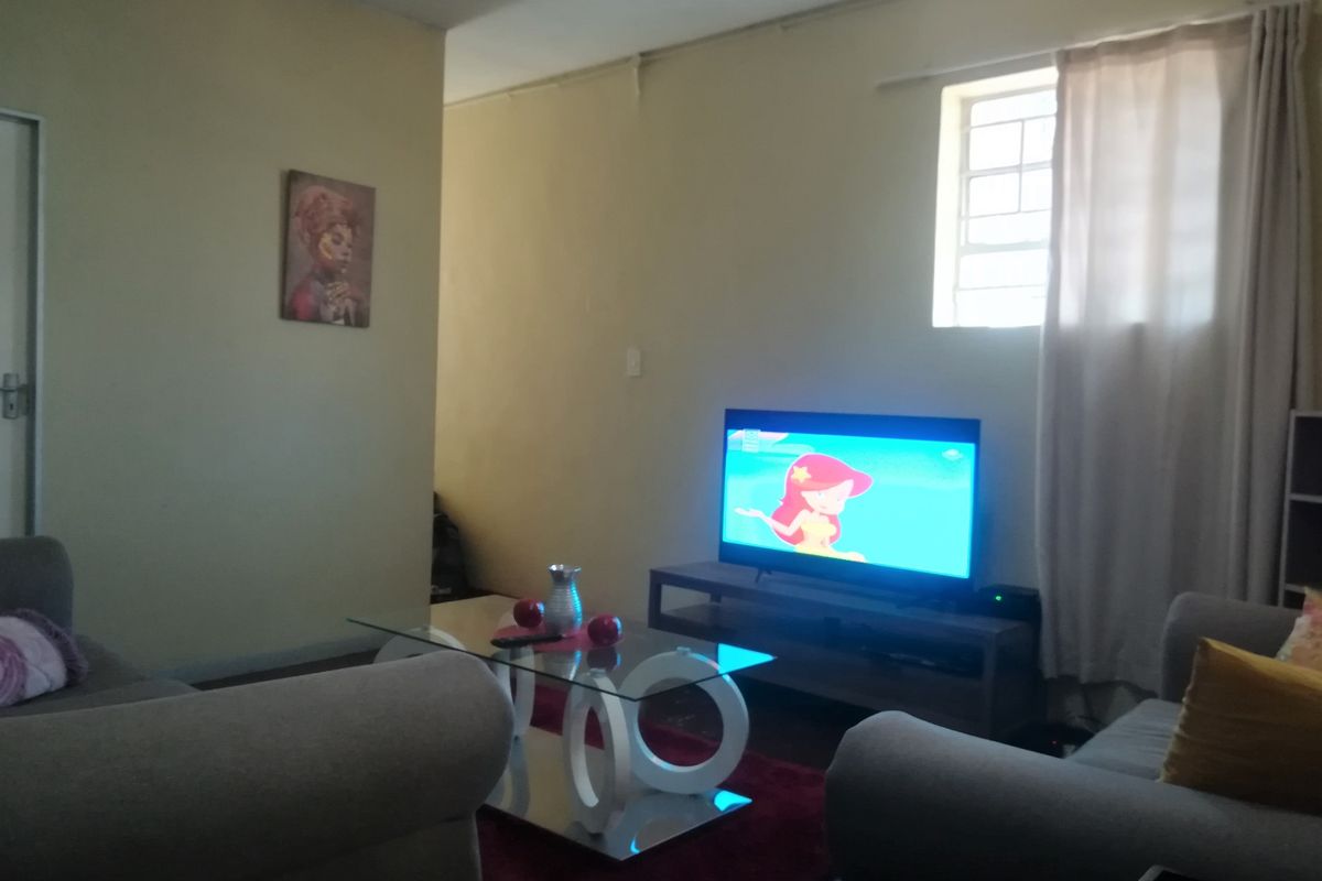 A living room area featuring neutral walls, a window with security bars, and standard interior finishes.