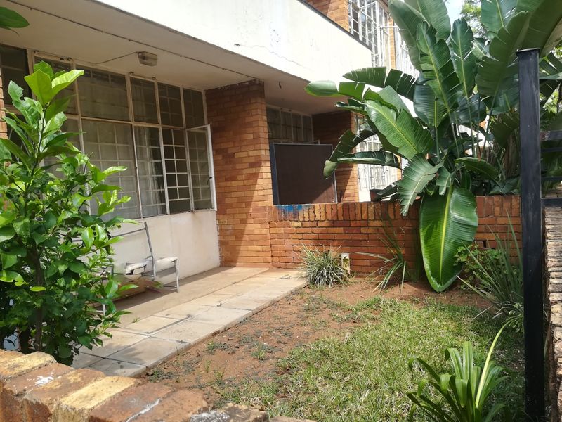 Ground floor patio area featuring brick construction and steel-framed windows, opening onto a small private garden space.