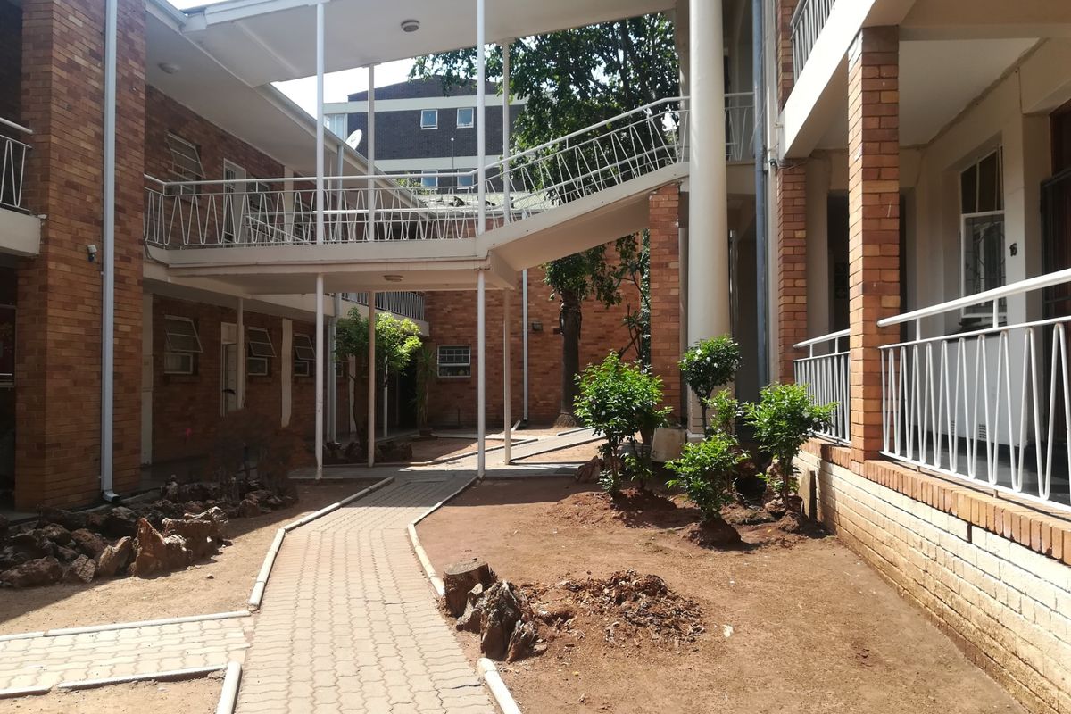 A view of the apartment complex courtyard featuring brick facades, paved walkways, and an elevated connecting bridge between building wings.