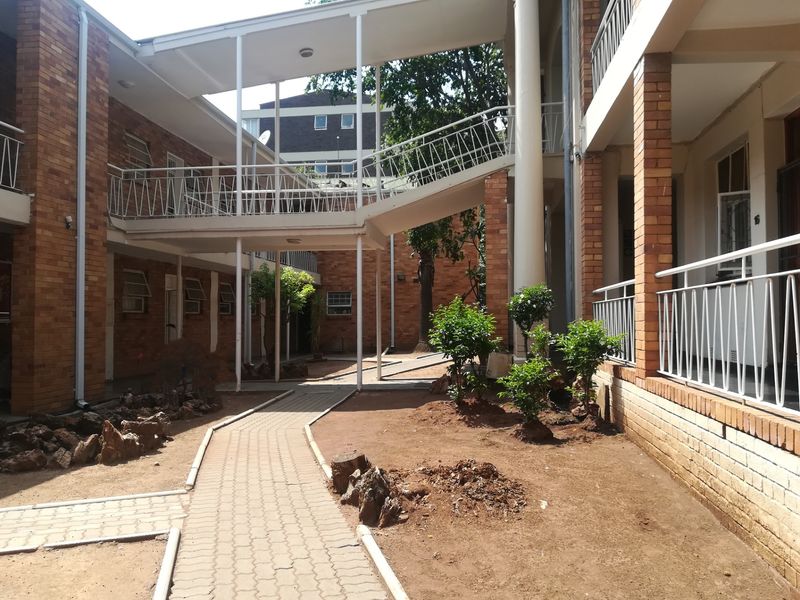 A view of the apartment complex courtyard featuring brick facades, paved walkways, and an elevated connecting bridge between building wings.
