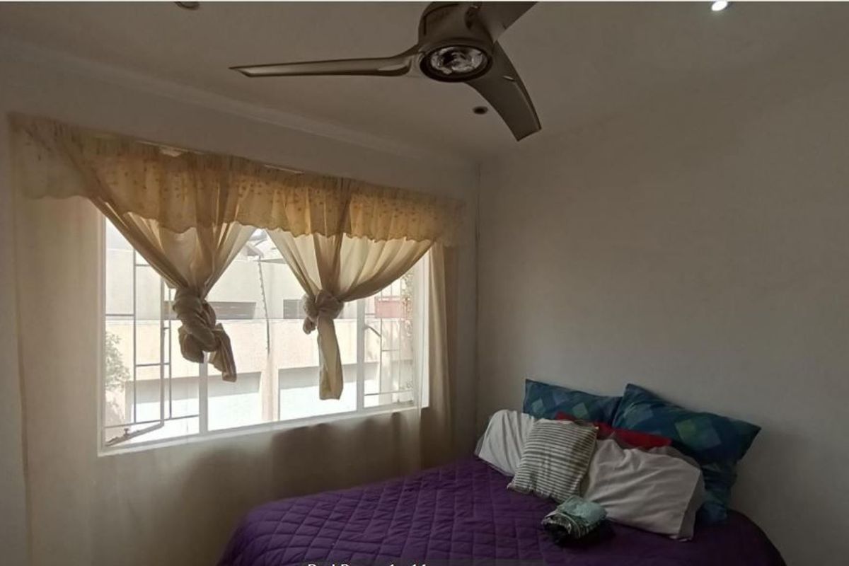 A bedroom featuring a ceiling fan, recessed lighting, and a window fitted with security bars.