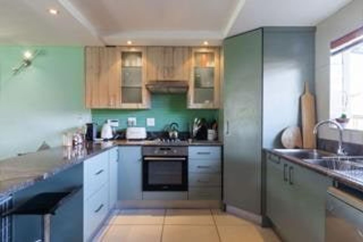 A functional kitchen featuring modern cabinetry, stone countertops, a built-in oven with gas hob, and a convenient breakfast bar for casual dining.
