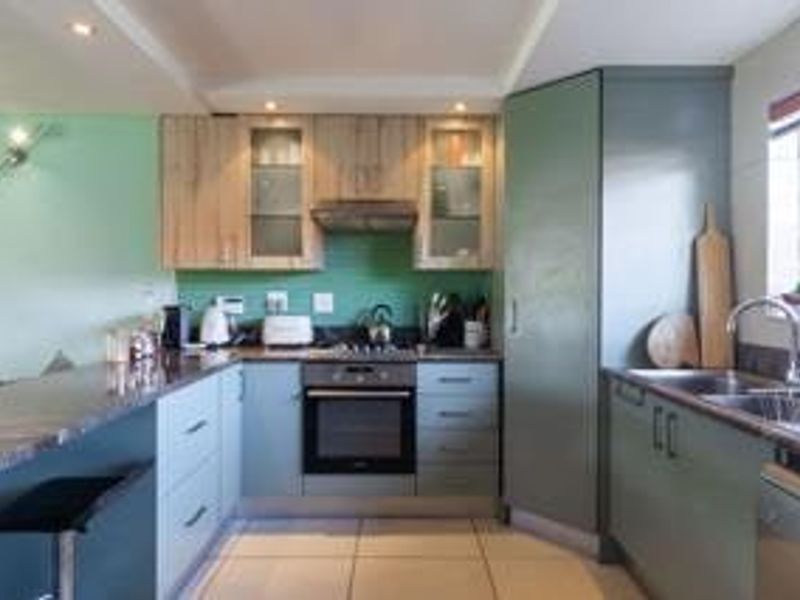 A functional kitchen featuring modern cabinetry, stone countertops, a built-in oven with gas hob, and a convenient breakfast bar for casual dining.