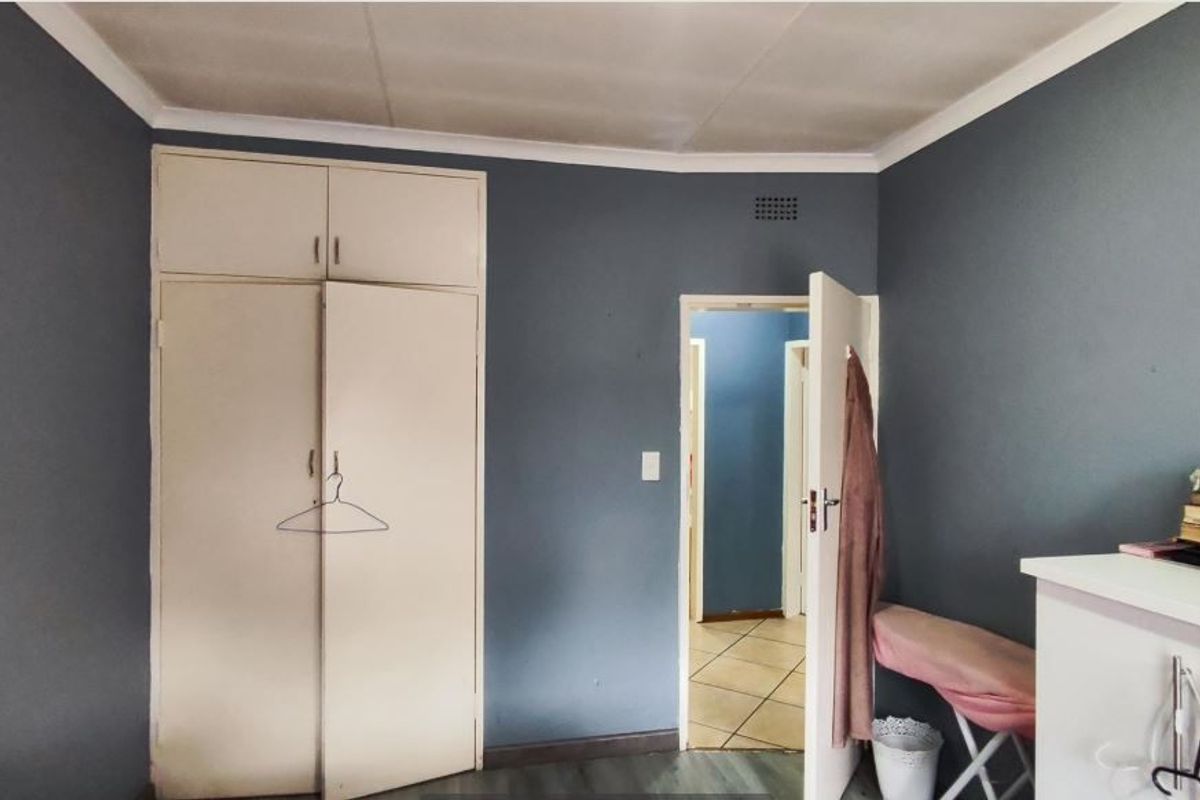 A bedroom featuring built-in cupboards and dark blue painted walls, providing a functional space with potential for cosmetic updates.