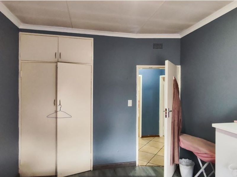 A bedroom featuring built-in cupboards and dark blue painted walls, providing a functional space with potential for cosmetic updates.