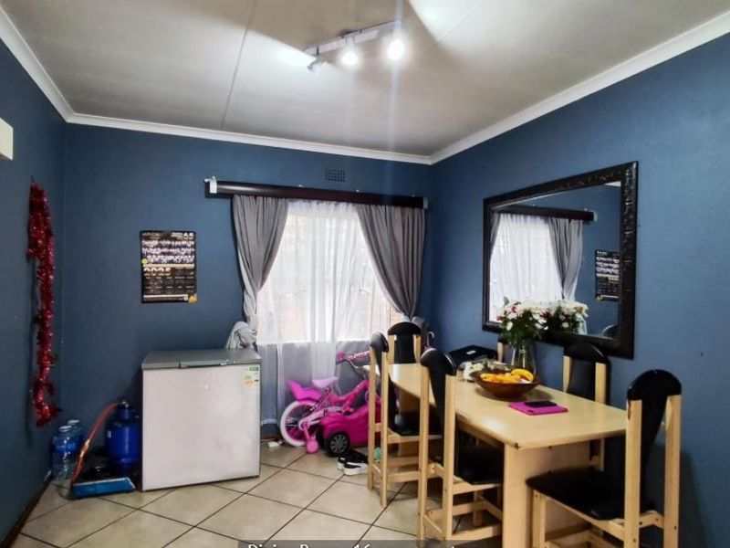 A dining room featuring ceramic floor tiles, coved ceilings, and track lighting, providing a functional space for meals.