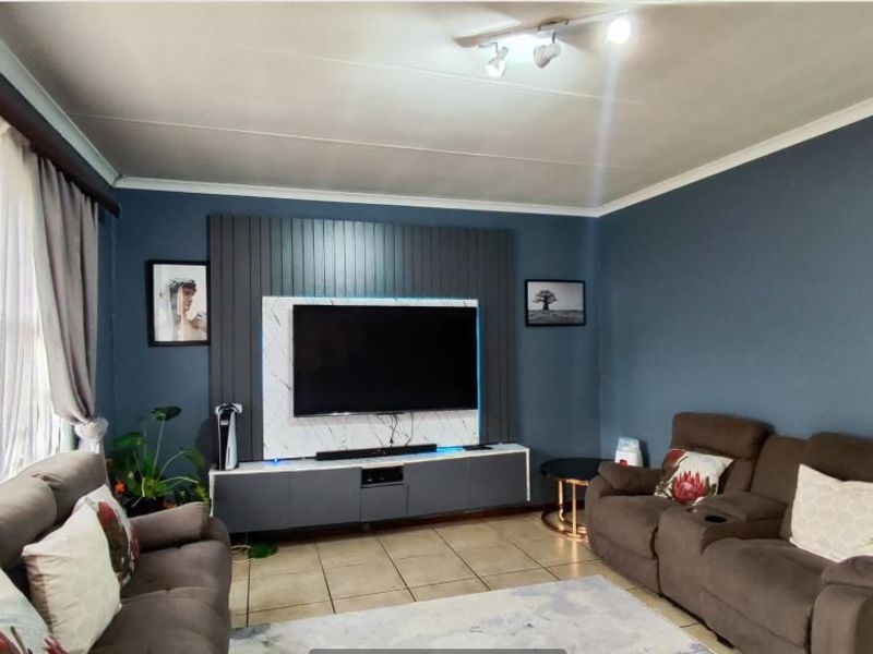 A comfortable living room featuring a modern built-in media wall, tiled flooring, and neutral wall tones, creating a functional and inviting space.