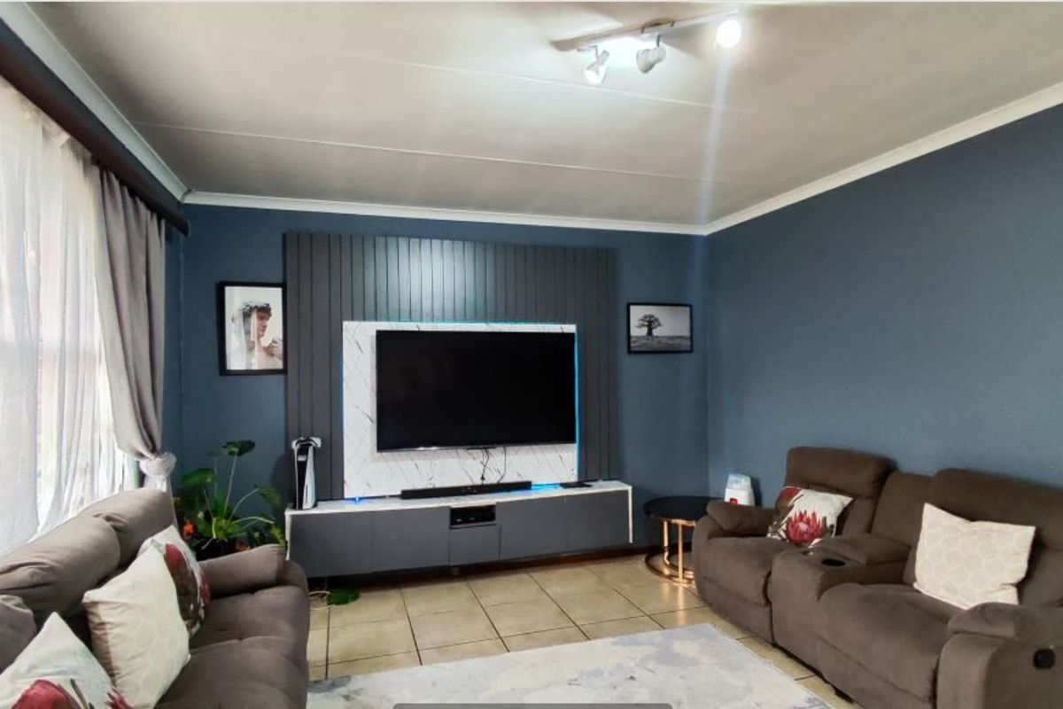 A comfortable living room featuring a modern built-in media wall, tiled flooring, and neutral wall tones, creating a functional and inviting space.