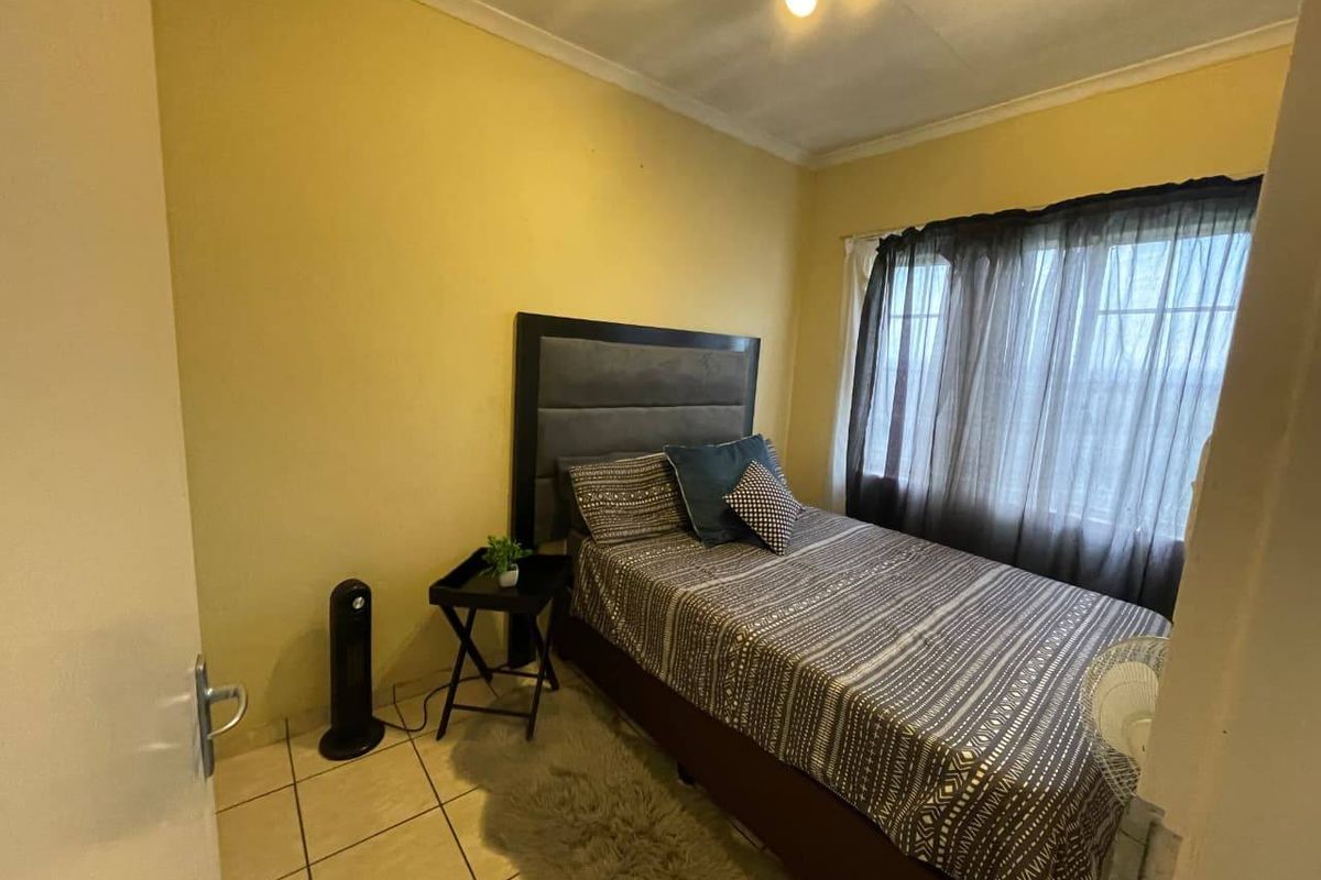 A compact bedroom featuring tiled flooring, a window with curtain tracks, and standard ceiling coving.