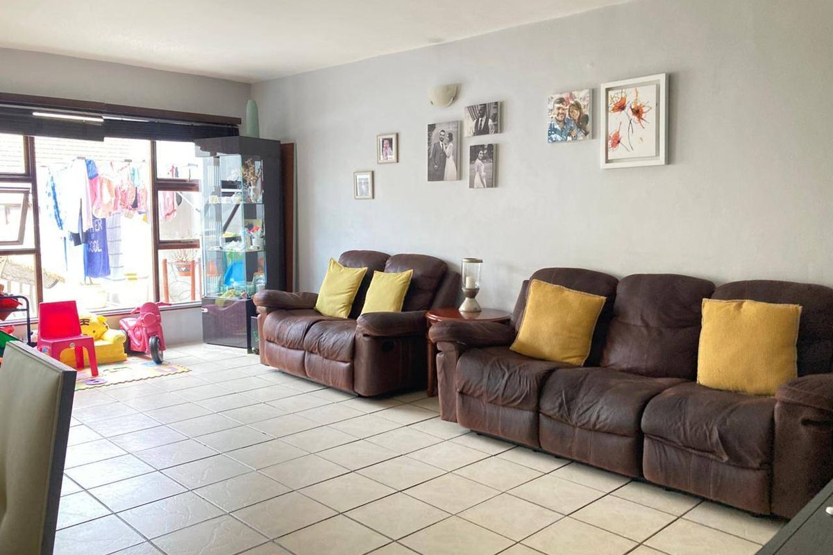 A spacious living room featuring neutral tiled flooring and a large sliding glass door providing natural light and access to the outdoor area.