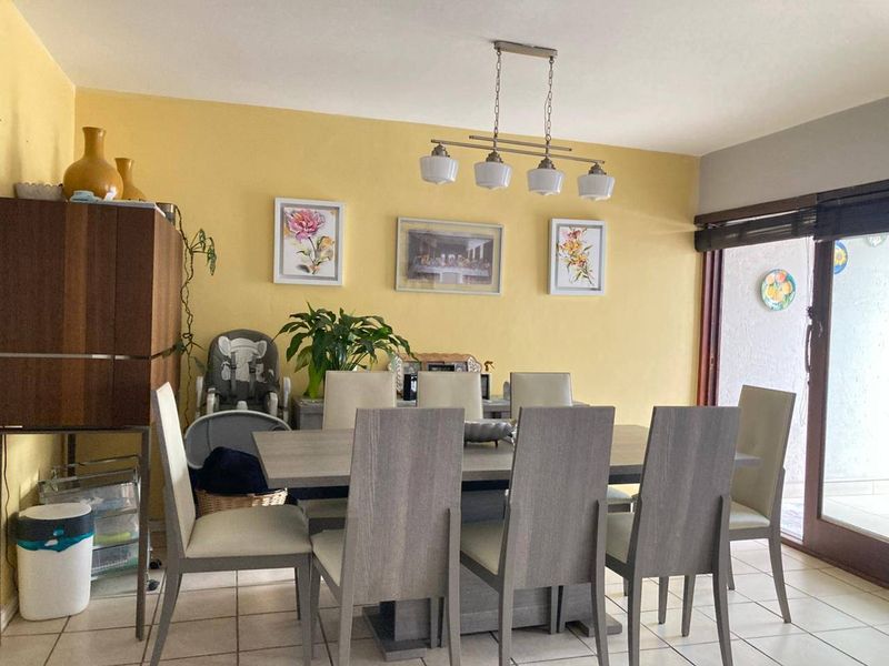 A dining room featuring tiled flooring, a central pendant light fixture, and a sliding glass door providing access to the outdoor area.