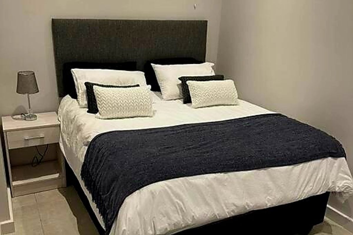 A well-maintained bedroom featuring neutral tiled flooring and fitted venetian blinds, providing a clean and functional living space.