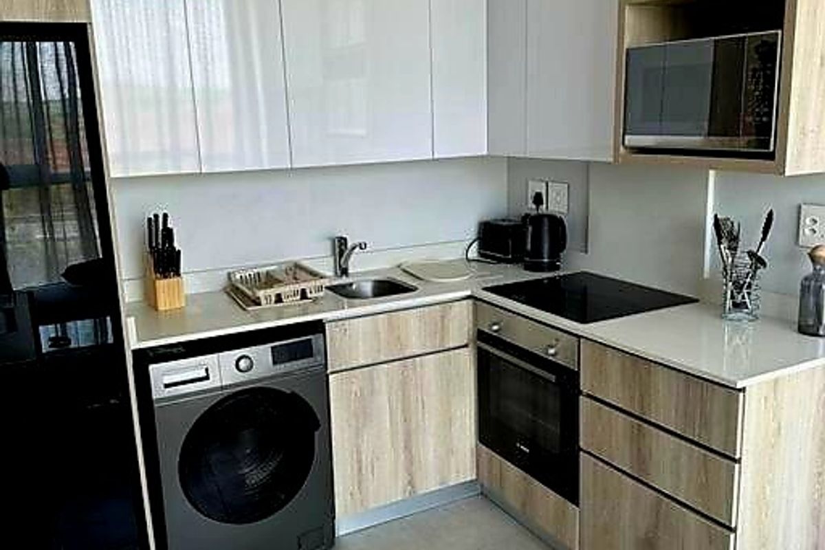 Modern kitchen featuring sleek white and wood-grain cabinetry, quartz countertops, integrated appliances, and contemporary tiled flooring.