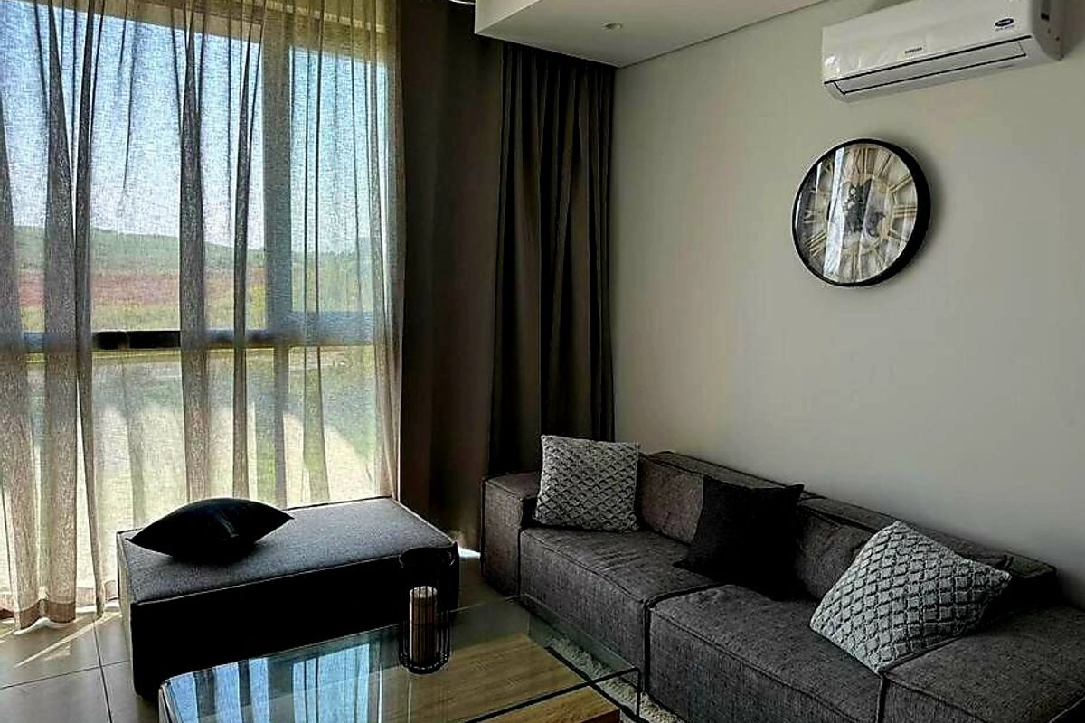 A modern living room featuring floor-to-ceiling windows, tiled flooring, and a wall-mounted split-system air conditioner.