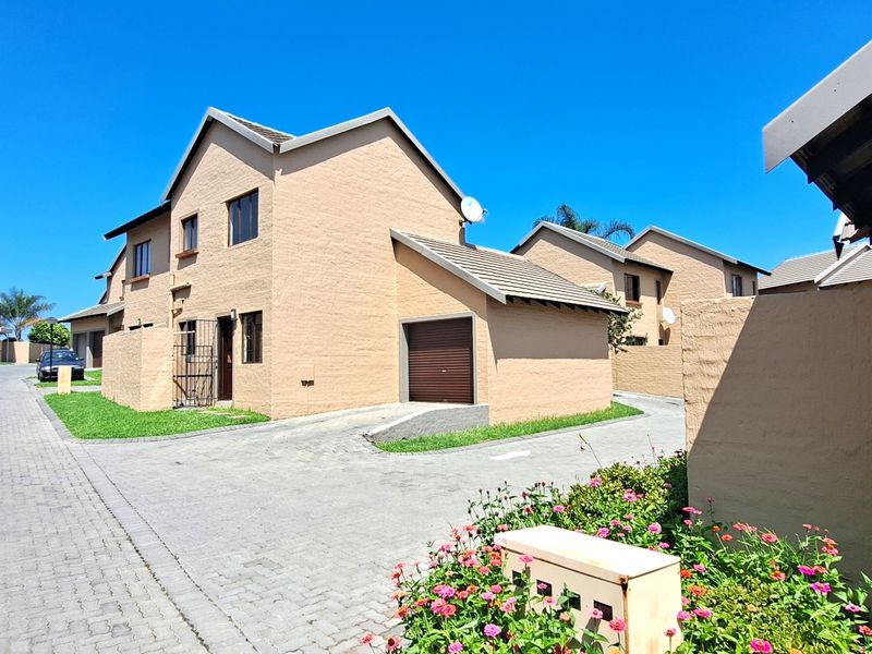 Exterior view of a townhouse featuring a paved driveway, single garage, and well-maintained brick facade within a residential complex.