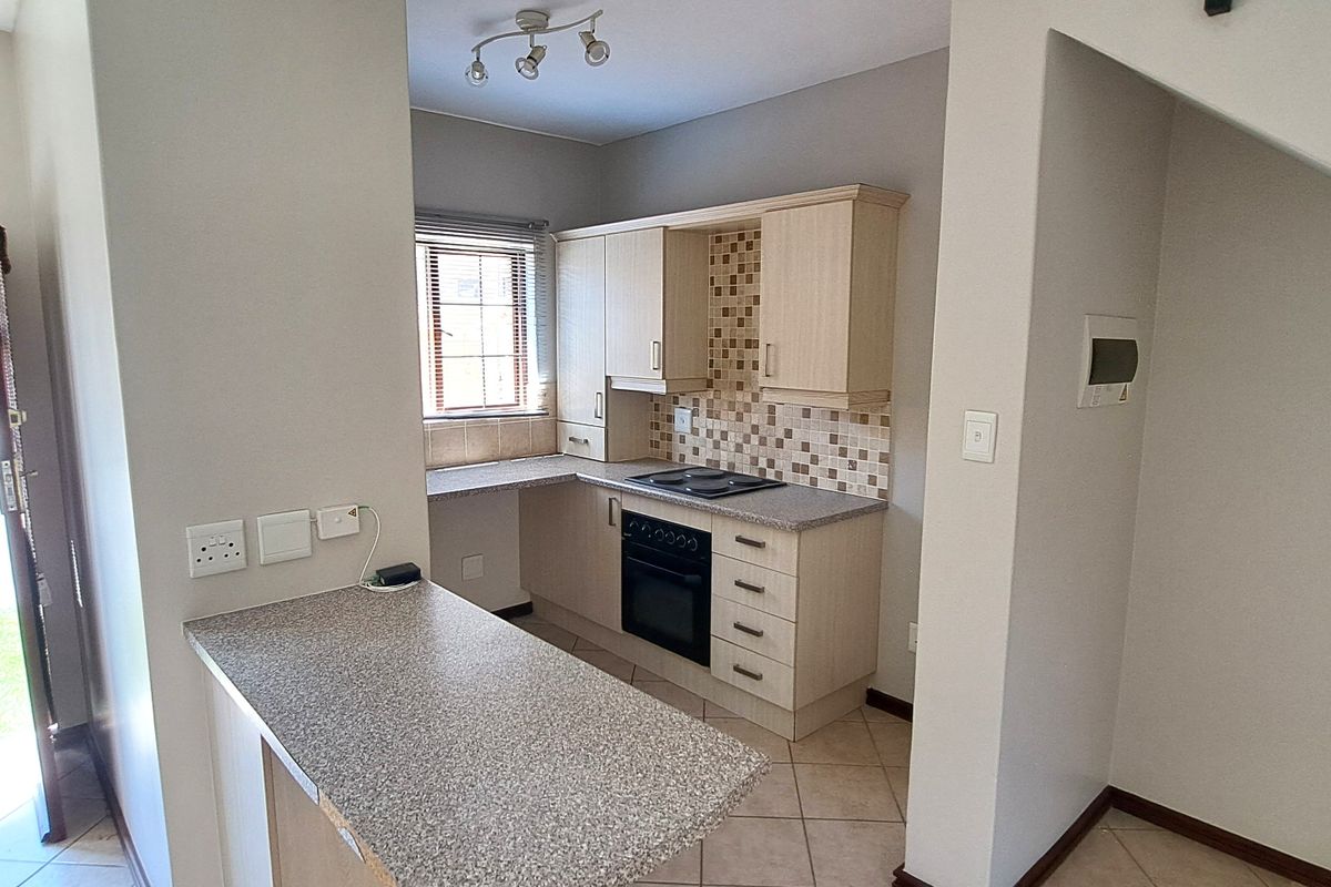 Compact kitchen featuring built-in cabinetry, laminate countertops, mosaic tile backsplash, and integrated electric oven and hob, with an adjoining breakfast nook.