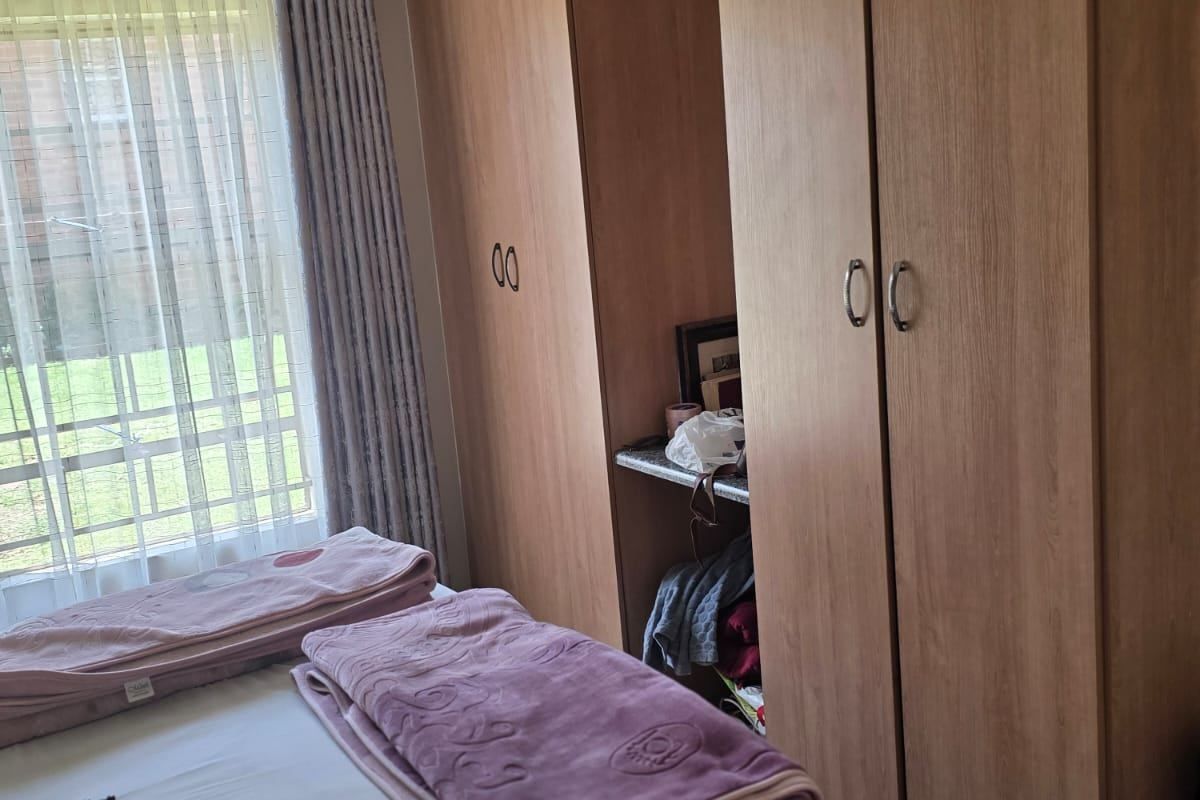 Bedroom featuring built-in wooden cabinetry and tiled flooring, offering ample storage space and natural light through the window.