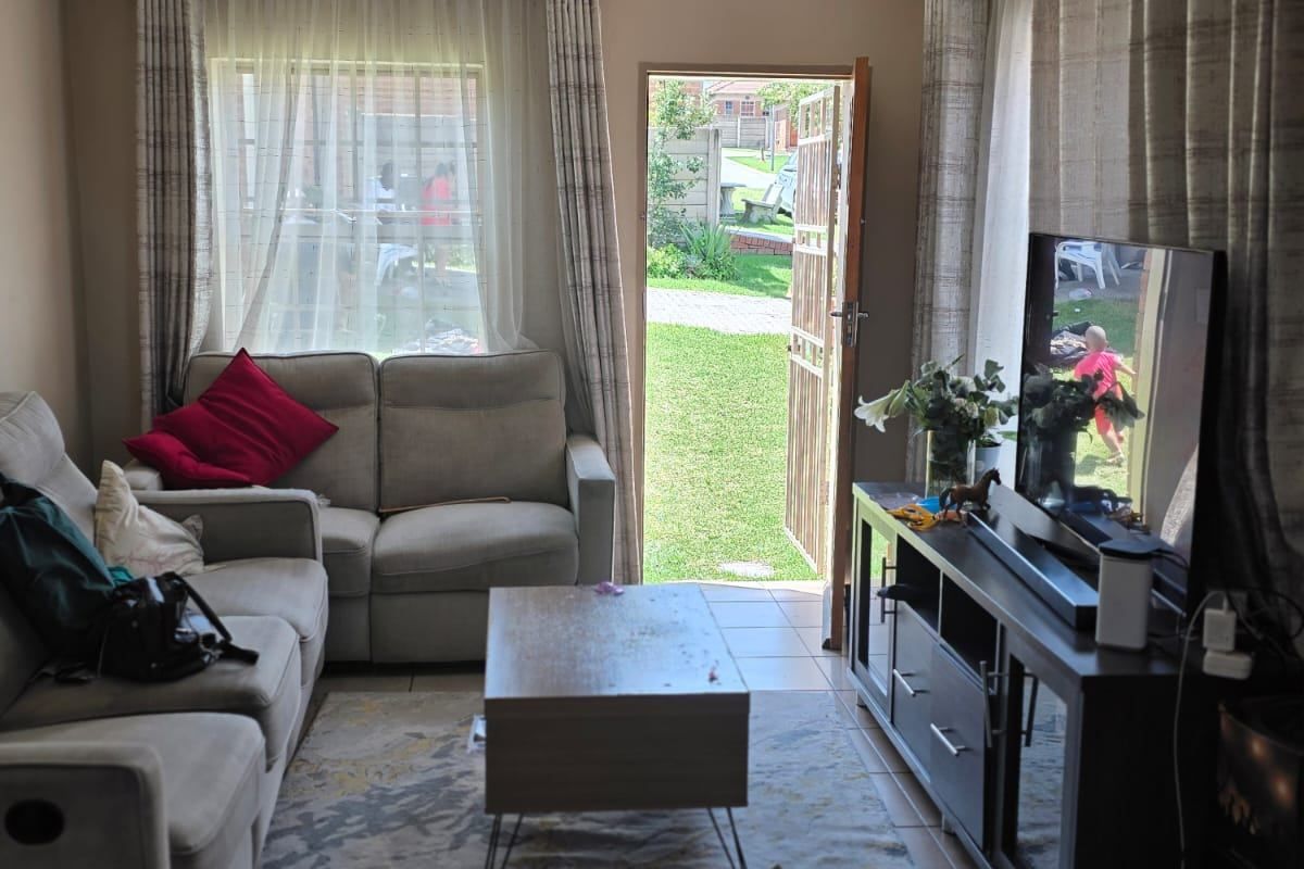 A comfortable living room featuring tiled flooring and direct access to the rear garden through a glass-panelled door.