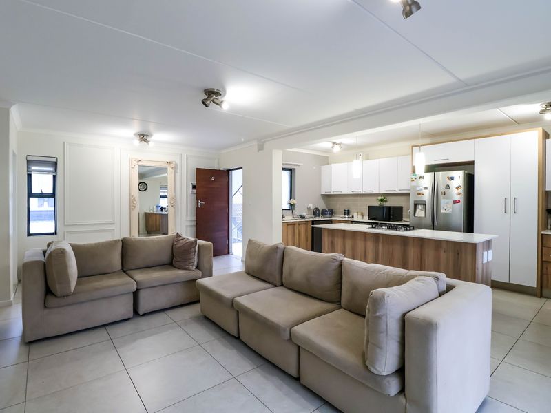 Spacious open-plan living area featuring a modern kitchen with a central island, ample cabinetry, and tiled flooring throughout.