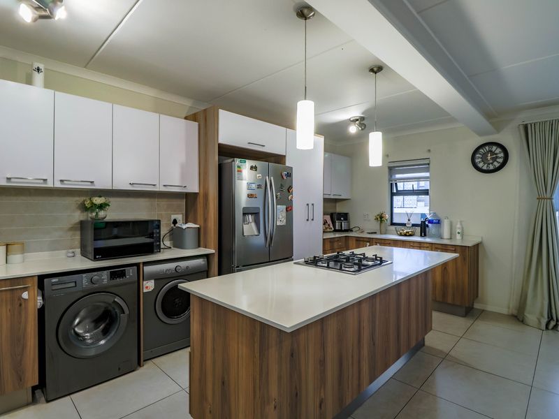 Modern kitchen featuring a central island with a gas hob, stone countertops, ample built-in cabinetry, and sleek pendant lighting.