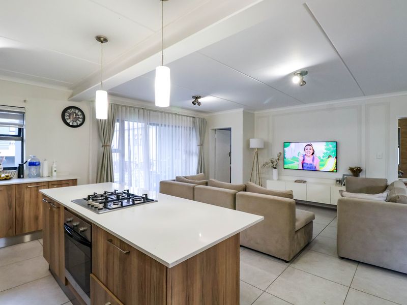 Modern open-plan living area featuring a kitchen island with a gas hob and oven, tiled floors, and seamless flow to the living space.