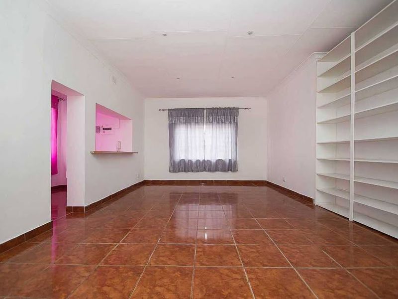 Spacious living area featuring tiled flooring, built-in shelving units, and a convenient serving hatch connecting to the kitchen area.