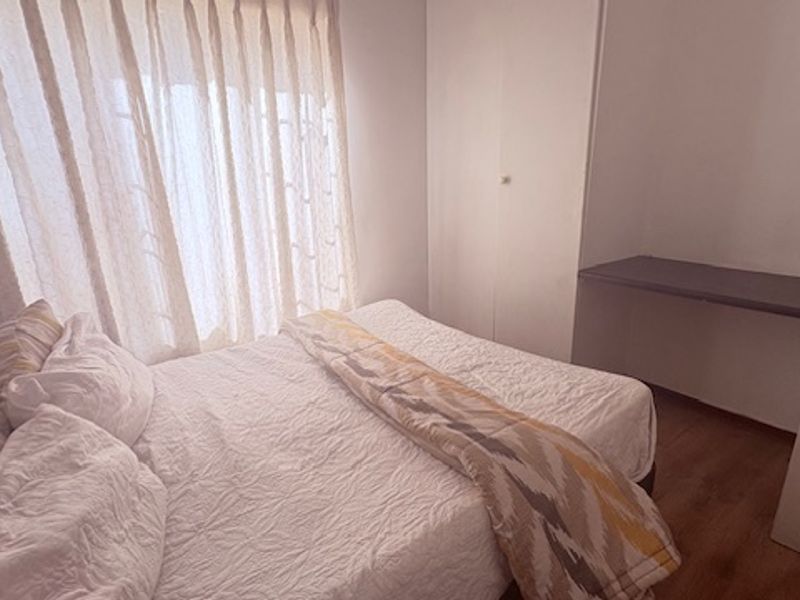 A functional bedroom featuring built-in cabinetry, a dedicated desk area, and wood-look flooring, offering a practical layout for a townhouse residence.